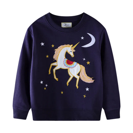 Mädchen in einem blauen Riesen Einhorn Sweatshirt mit detaillierter Einhorn-Stickerei, das fröhlich in die Kamera lächelt.