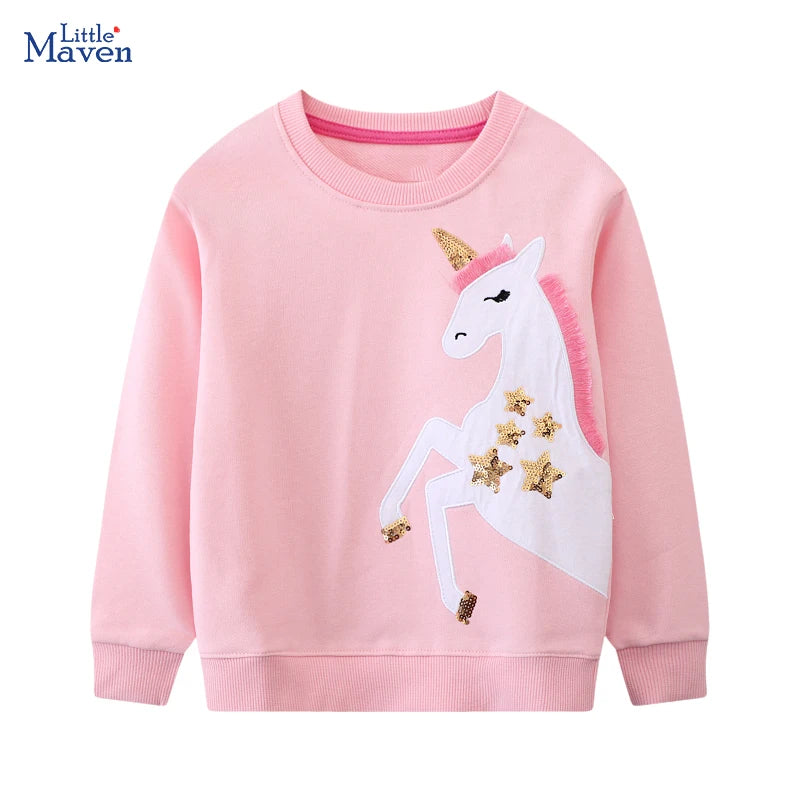 Mädchen trägt einen rosafarbenen Einhorn Pullover mit einer Einhorn-Stickerei und glitzernden Pailletten-Sternen