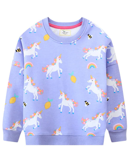 Mädchen in einem pinken Riesen Einhorn Sweatshirt mit einem großen, farbenfrohen Einhorn-Motiv auf der Vorderseite, lächelnd.