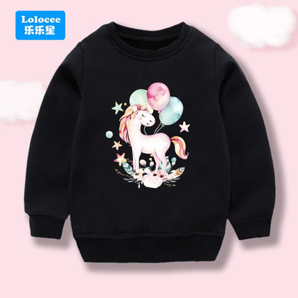 Kind trägt einen schwarzen Einhorn Hoodie mit einem großen, bunten Cartoon-Ballon-Einhorn-Motiv auf der Brust, das Lachen ins Gesicht zaubert.