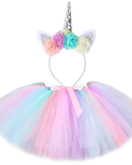 Mädchen in einem farbenfrohen Einhorn Kostuem Tutu Rock Set mit passendem Stirnband