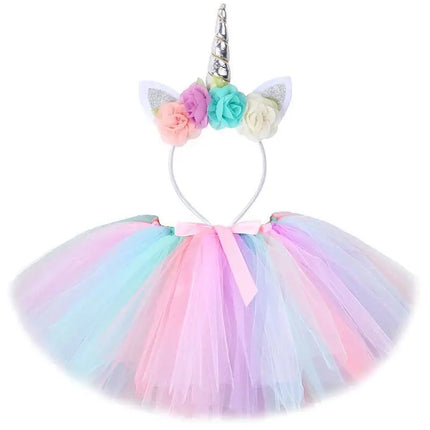 Mädchen in einem farbenfrohen Einhorn Kostuem Tutu Rock Set mit passendem Stirnband