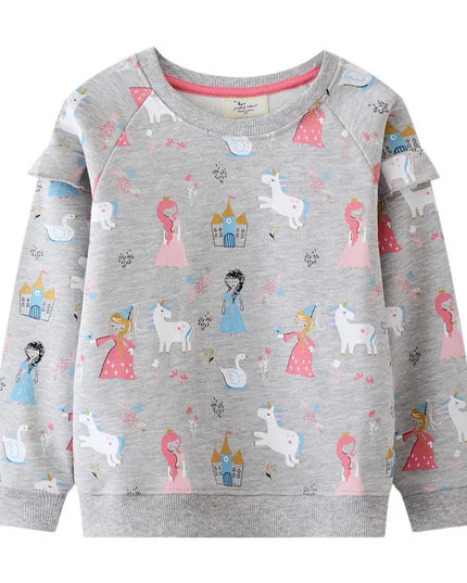 Mädchen in einem grauen Riesen Einhorn Sweatshirt mit einer detaillierten und farbenfrohen Einhorn Stickerei, die lächelnd posiert.