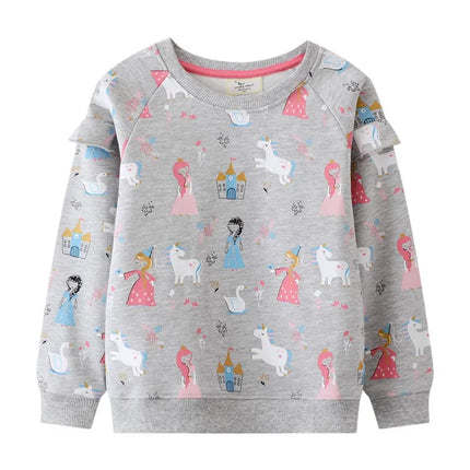 Mädchen in einem grauen Riesen Einhorn Sweatshirt mit einer detaillierten und farbenfrohen Einhorn Stickerei, die lächelnd posiert.