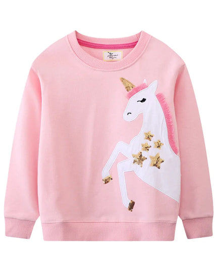 Mädchen in einem blauen Riesen Einhorn Sweatshirt mit farbenfroher Einhorn Stickerei, das fröhlich lächelt und spielt.