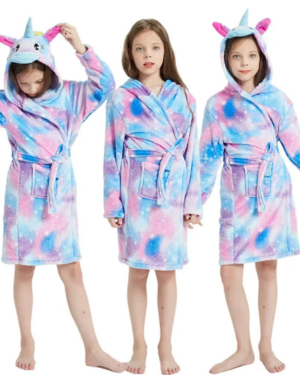 Mädchen in einem flauschigen Einhorn Pyjama in hellen Farben, gemütlich auf einem Sofa sitzend