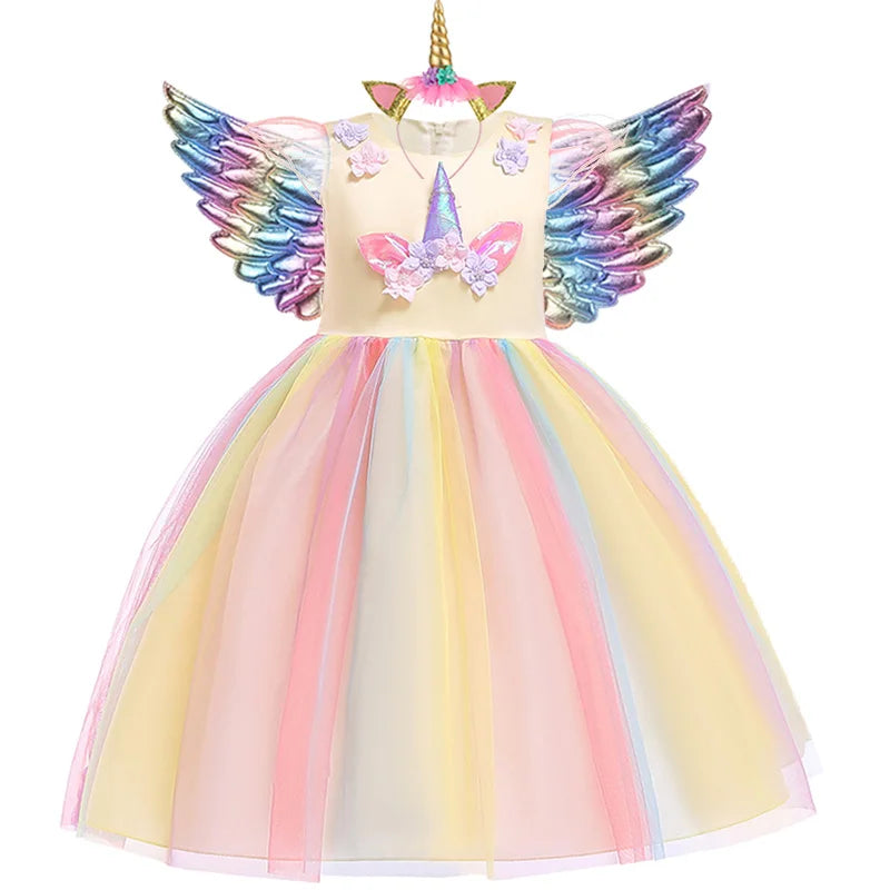 Mädchen in einem gelb-pinken Einhorn Kostüm Regenbogen Tutu-Kleid mit Stirnband und Flügeln, lachend und spielend