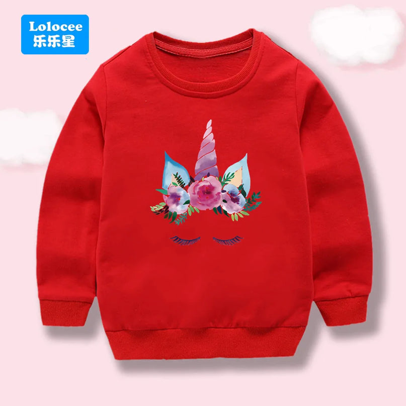 Mädchen trägt leuchtend roten Einhorn Hoodie mit großem, buntem Cartoon-Einhorn-Motiv auf der Brust