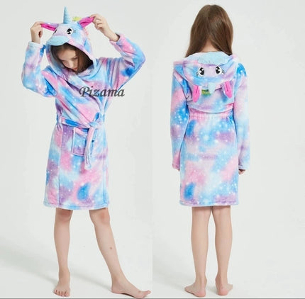 Mädchen in einem pinkfarbenen Einhorn Pyjama mit Sternenmuster und Kapuze, kuschelt sich gemütlich ein.