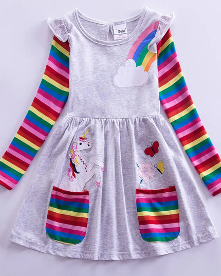 Mädchen in einem grauen Einhorn Kleid mit langen, bunten Regenbogenärmeln und gesticktem Einhorn-Motiv für den Herbst.