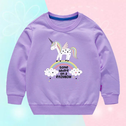 Mädchen trägt einen lila Einhorn Pullover mit einem großen, lächelnden Einhorn-Gesicht und Sternen