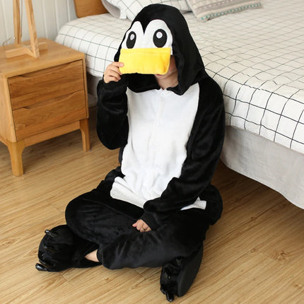 Glückliches Model in einem schwarzen Einhorn Onesie im Pinguin-Look mit Kapuze und orangefarbenem Schnabel