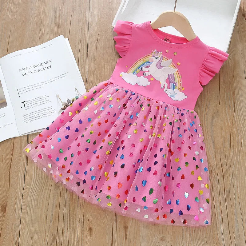 Mädchen in einem rosafarbenen Riesen Einhorn Regenbogenkleid mit fliegenden Ärmeln und einem glitzernden Mesh-Rock, verspielt lächelnd.