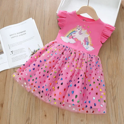 Mädchen in einem rosafarbenen Riesen Einhorn Regenbogenkleid mit fliegenden Ärmeln und einem glitzernden Mesh-Rock, verspielt lächelnd.