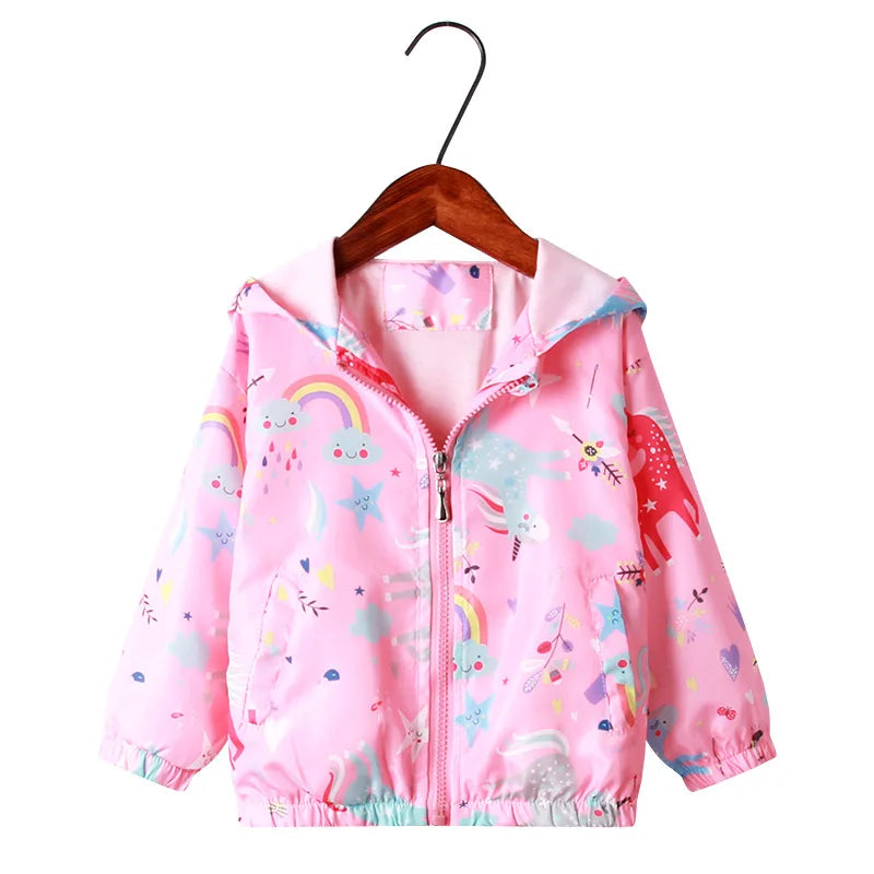 Mädchen in einer rosa Einhorn Jacke mit Regenbogen-Muster und Kapuze, fröhlich lachend